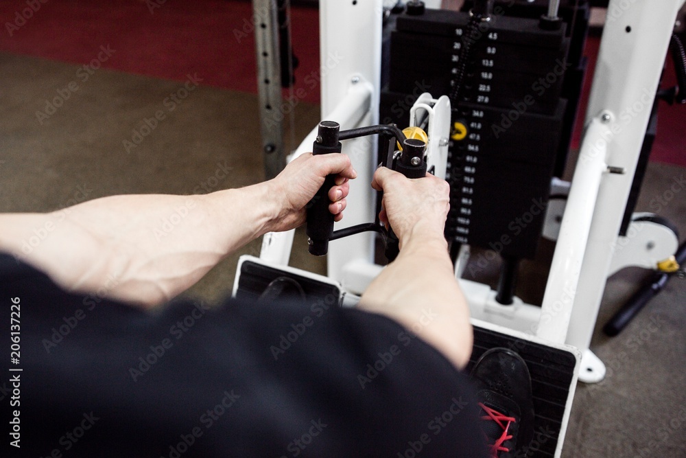 Muscular man doing exercises on his hands on the simulator in the gym close-up