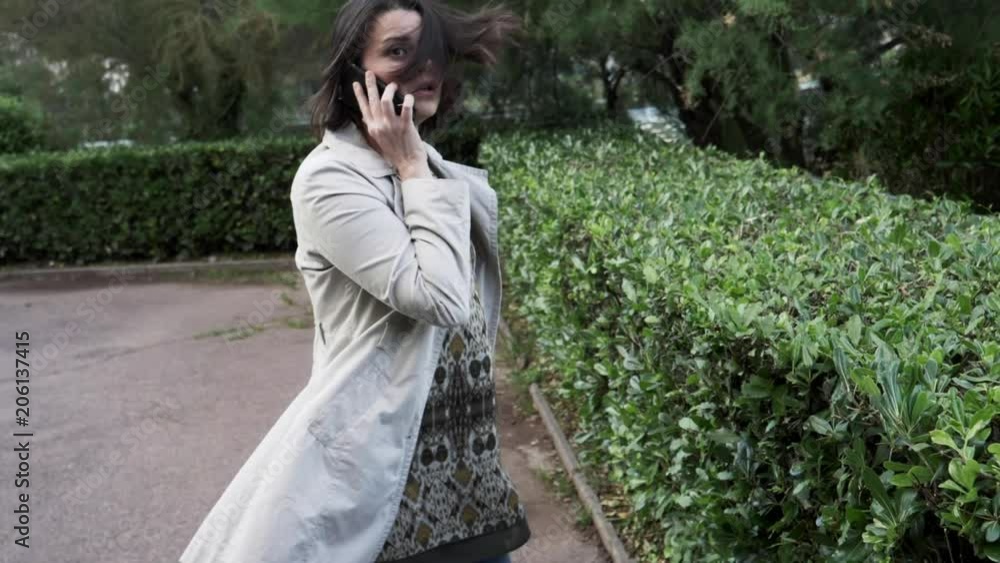 Woman on the phone in city scared of aggression running away slow motion medium shot Woman on the phone in city scared of aggression running away slow motion medium shot