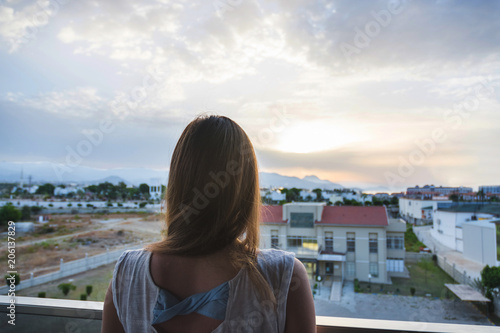 A girl in the summer looks at the sunrise in the mountains at sea, the view from behind. Turkey, Alanya
