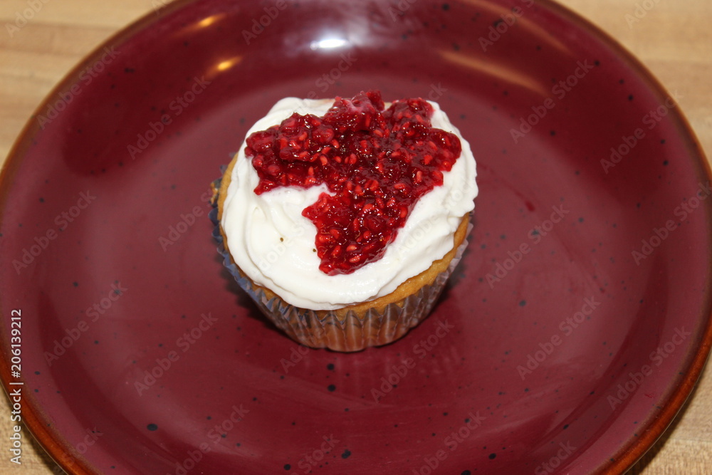Top of Vanilla Raspberry Cupcake on a red plate Top of Vanilla Raspberry Cupcake on a red plate