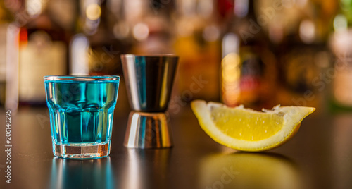 Popular blue drink shot kamikaze on the background of the bar with bottles  a refreshing drink