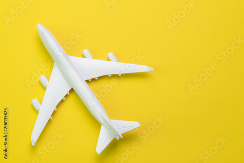 Travel, tourism or transportation concept, white toy airplane on vibrant and vivid yellow background with copy space