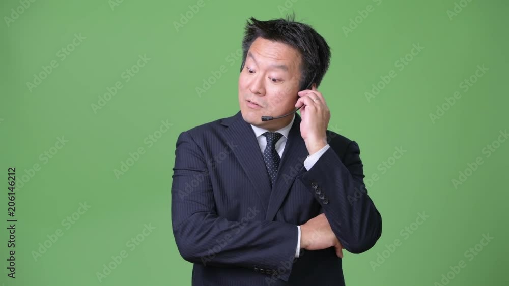 Mature Japanese businessman against green background Mature Japanese businessman against green background