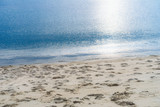 blue sea with sun light reflection and beach sand