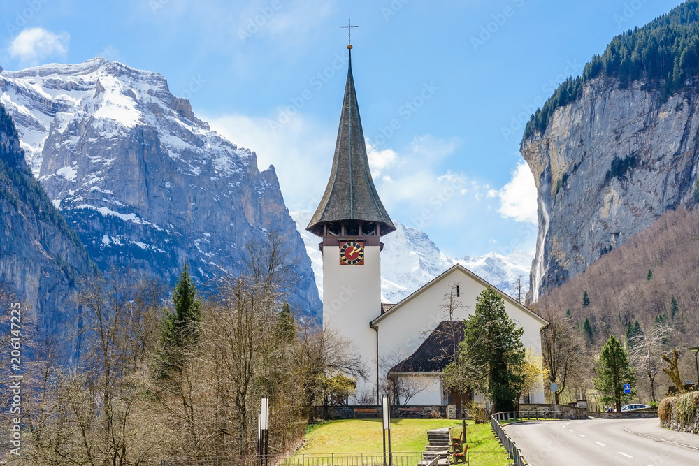 Sunny summer view of amazing touristic alpine village with famous church and Staubbach waterfall, Lauterbrunnen, Switzerland, Europe
