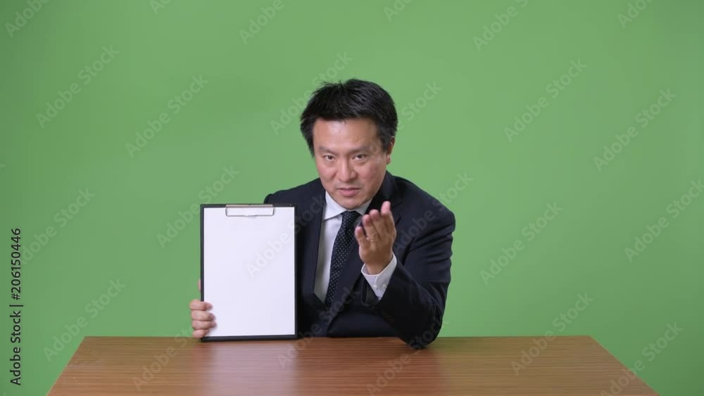 Mature Japanese businessman against green background Mature Japanese businessman against green background