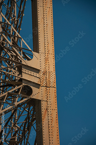 View of one leg’s iron structure of the Eiffel Tower, with sunny blue sky in Paris. Known as the “City of Light”, is one of the most impressive world’s cultural center. Northern France.