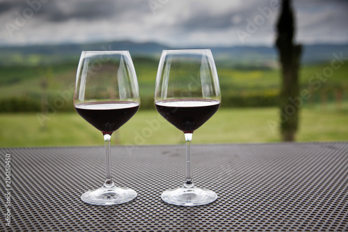 two glasses of red wine against beautiful landscape in Tuscany