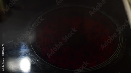 Modern electric hob being turned on and glowing bright red with heat before cooking in the kitchen.