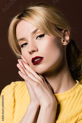 portrait of seductive blonde girl looking at camera isolated on brown