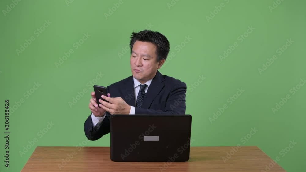 Mature Japanese businessman against green background Mature Japanese businessman against green background