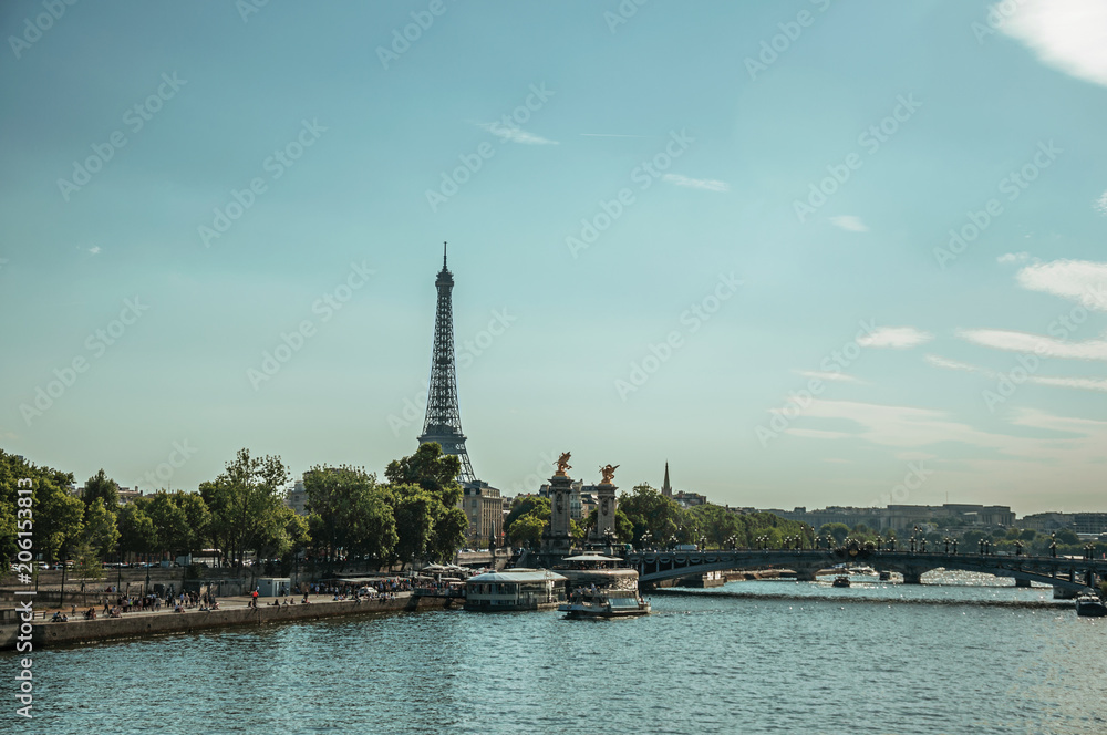 Seine River bank with boats, trees, bridge and the Eiffel Tower at sunset in Paris. Known as the “City of Light”, is one of the most impressive world’s cultural center. Northern France.