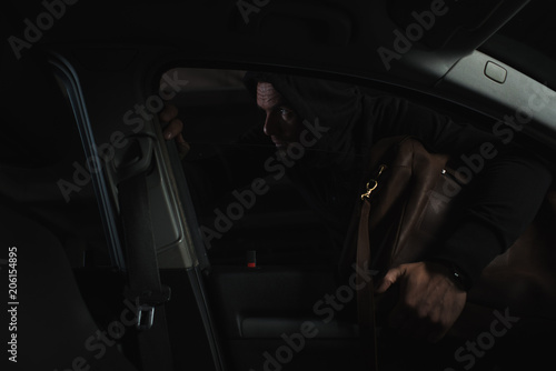 cautious male thief in black hoodie stealing bag from car © LIGHTFIELD STUDIOS