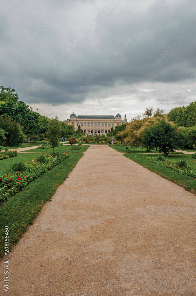 Path with building in the background and grassy wooded yard in the Garden of Plants in Paris. Known as the “City of Light”, is one of the most impressive world’s cultural center. Northern France.