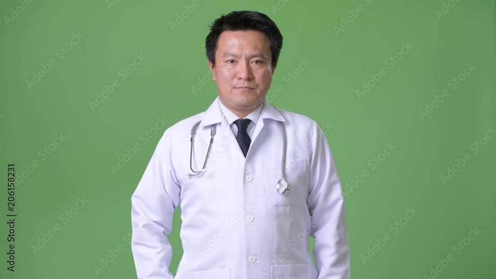 Mature Japanese man doctor against green background Mature Japanese man doctor against green background