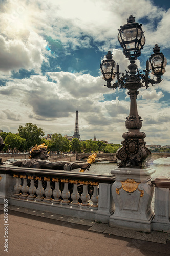Golden statue and lighting post adorning the Alexandre III bridge over the Seine River and Eiffel Tower in Paris. Known as one of the most impressive world’s cultural center. Retouched photo.