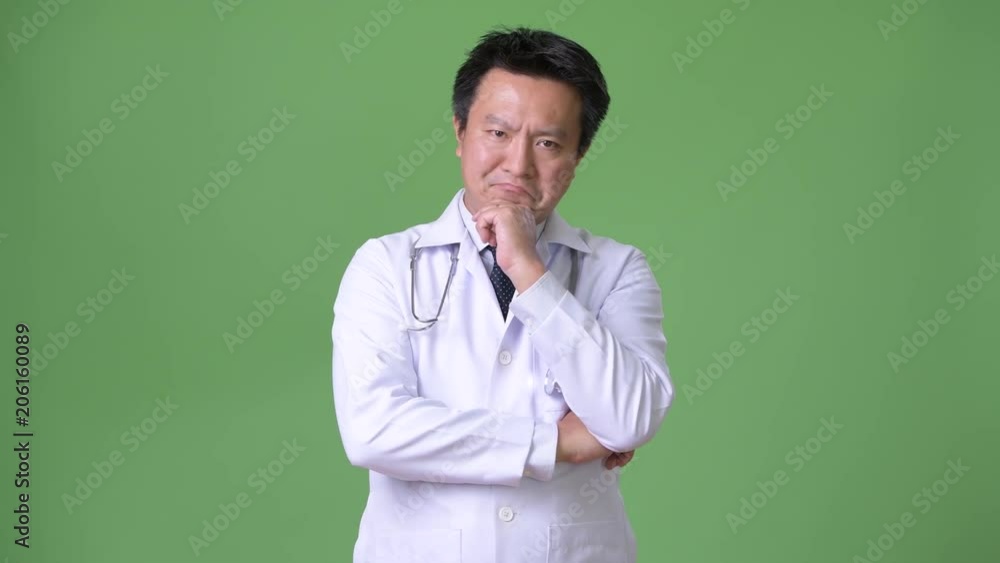 Mature Japanese man doctor against green background Mature Japanese man doctor against green background
