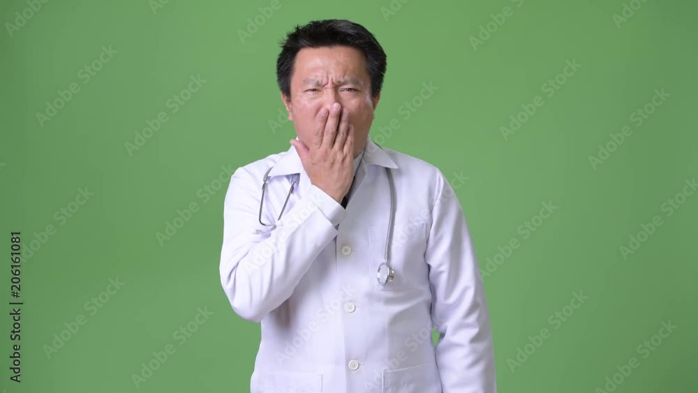 Mature Japanese man doctor against green background Mature Japanese man doctor against green background