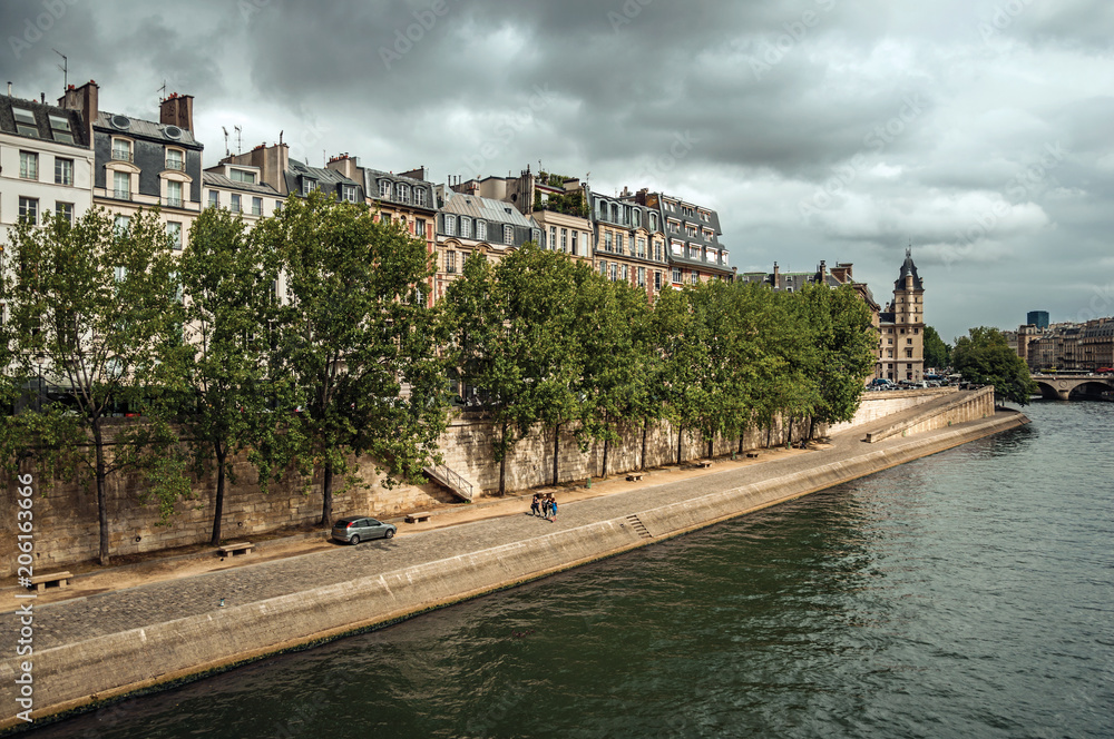 Old buildings, promenade and lined trees on the bank of Seine River with sunlight in Paris. Known as the “City of Light”, is one of the most impressive world’s cultural center. Northern France. Old buildings, promenade and lined trees on the bank of Seine River with sunlight in Paris. Known as the “City of Light”, is one of the most impressive world’s cultural center. Northern France.
