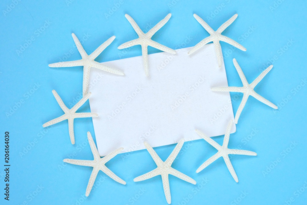 summer sea frame.white board with white dry starfish on a bright blue background.top view, copy space.Summer time. Summer season summer sea frame.white board with white dry starfish on a bright blue background.top view, copy space.Summer time. Summer season