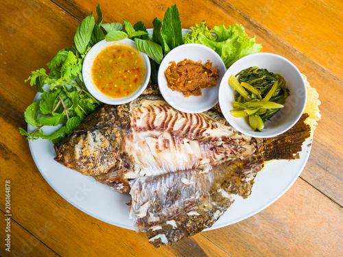 Thai food, tilapia fresh fish grilled with salt and dips in on wooden table by topview photo