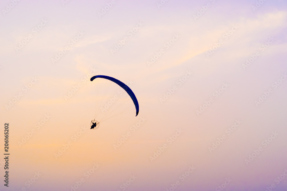 A paraglider flying at sunset sky background, active rest outdoors, extreme sports, extreme sport