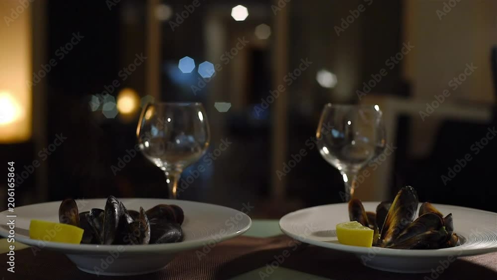 Two plates with hot mussels with the steam above and wine glasses. Romantic date for couple. Family dinner. Two plates with hot mussels with the steam above and wine glasses. Romantic date for couple. Family dinner.