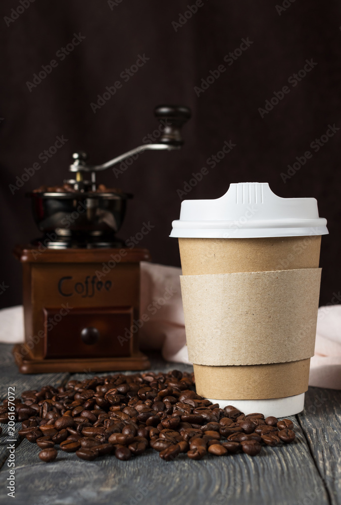 Container with lid for takeaway coffee, near coffee beans and mill