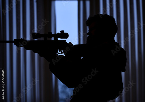 Canvas Print Silhouette of macho aiming at victim in front of window