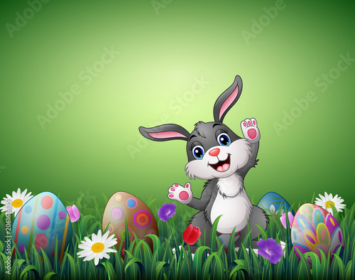 Happy Easter bunny with decorated Easter eggs in a grass field