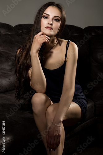 Sensual attractive young woman in a silk pajamas poses on a sofa. © sandyche
