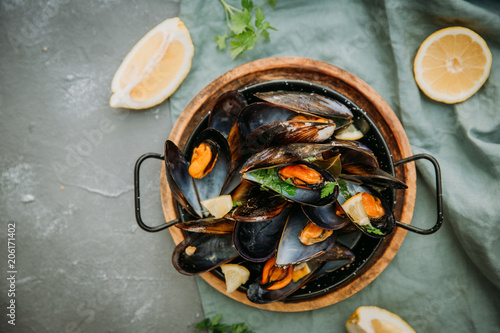 Traditional blue mussel in white wine on stone background, top vie, copy space