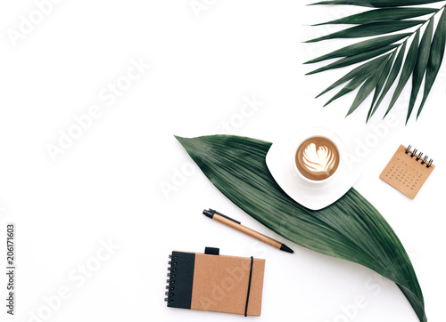 Creative flat lay background for blogger, keyboard, coffee cup and headphones with green leaves. Minimal workspace photo