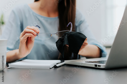 Woman cleaning reading glasses with cloth
