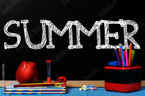 Text Summer on black chalkboard with school accessories