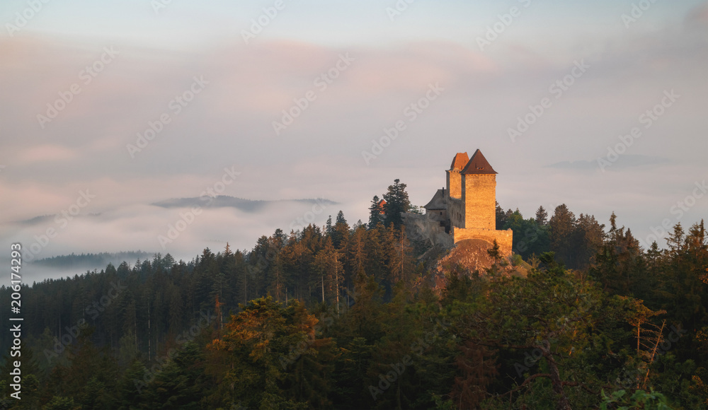 Obraz premium Sunrise in Kasperk castle, Sumava, Czech Republic. Hills and villages in the fog, misty view on Czech landscape, evening scene.