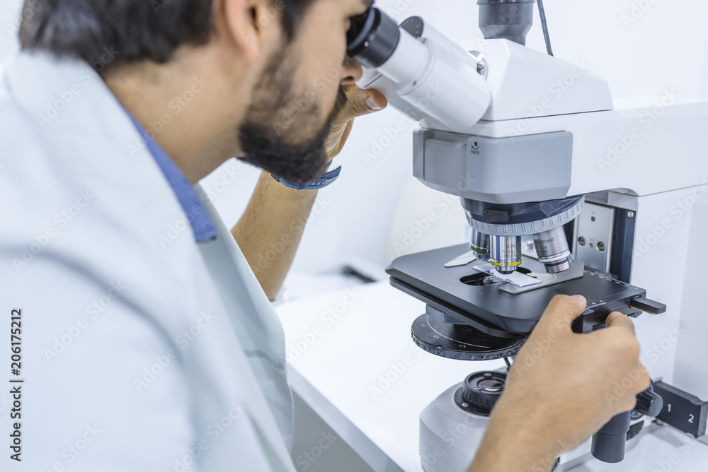 Scientist looking through a microscope in a laboratory Scientist looking through a microscope in a laboratory