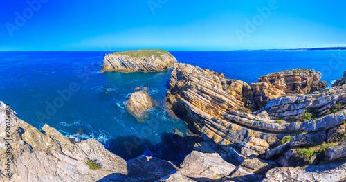 Wonderful romantic panoramic landscape. Coastline of island Baleal of the Atlantic ocean near Peniche. Famous geological sediments sandstone tilts rocks. West coast of Portugal at sunny weather.