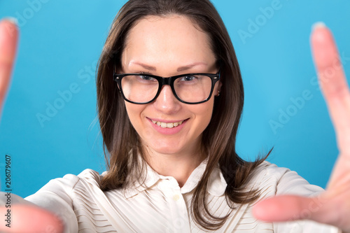 Close up portrait of a beautiful brunette woman in glasses on a blue background.