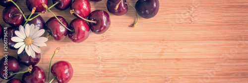 Cherries and daisy on wood background with copy space