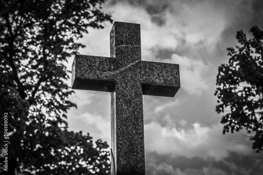 Black white shot of a stone cross on the background of trees - the concept of Christian faith Black white shot of a stone cross on the background of trees - the concept of Christian faith