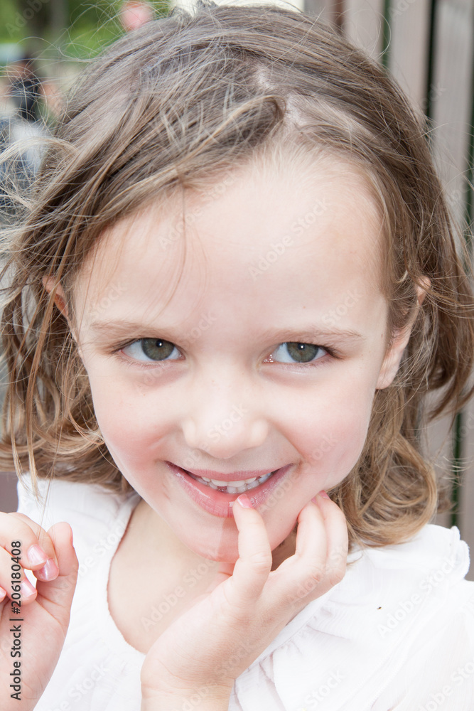 Outdoor portrait of a cute little girl standing against old wooden background Outdoor portrait of a cute little girl standing against old wooden background