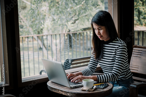 Woman freelancer is working and hands typing keyboard on a new project on laptop computer in cafe