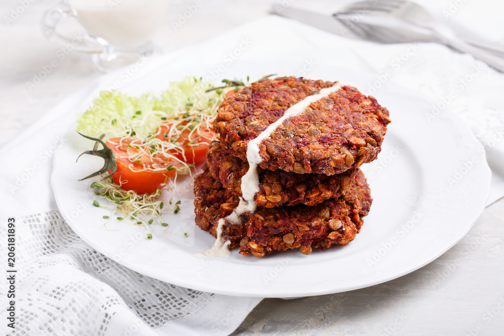 Vegan burgers from lentils, oats and vegetables. Veggie cutlets served with green salad and tomatoes. Vegan burgers from lentils, oats and vegetables. Veggie cutlets served with green salad and tomatoes.