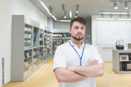 Portrait of man tech consultant. The consultant poses to the camera on the background of a light electronics store. photo