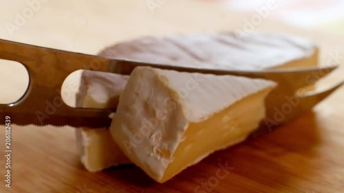 Woman cutting round cheese brie with a special knife photo