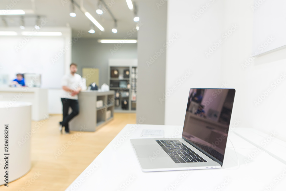 Laptop on the showcase in the technology store. Laptop on the background of a bright modern electronics store. Laptop on the showcase in the technology store. Laptop on the background of a bright modern electronics store.