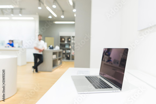 Laptop on the showcase in the technology store. Laptop on the background of a bright modern electronics store. © bodnarphoto