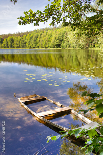 Fototapeta Naklejka Na Ścianę i Meble -  Masurian lake and a fishing boot. Colorful leaves, blue water and sunny skies with some white clouds. Masuria region, Poland.
