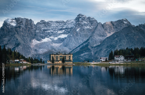 View of Misurina lake with large building of Institute Pius XII through bushes at sunset. Dolomites  Italy.